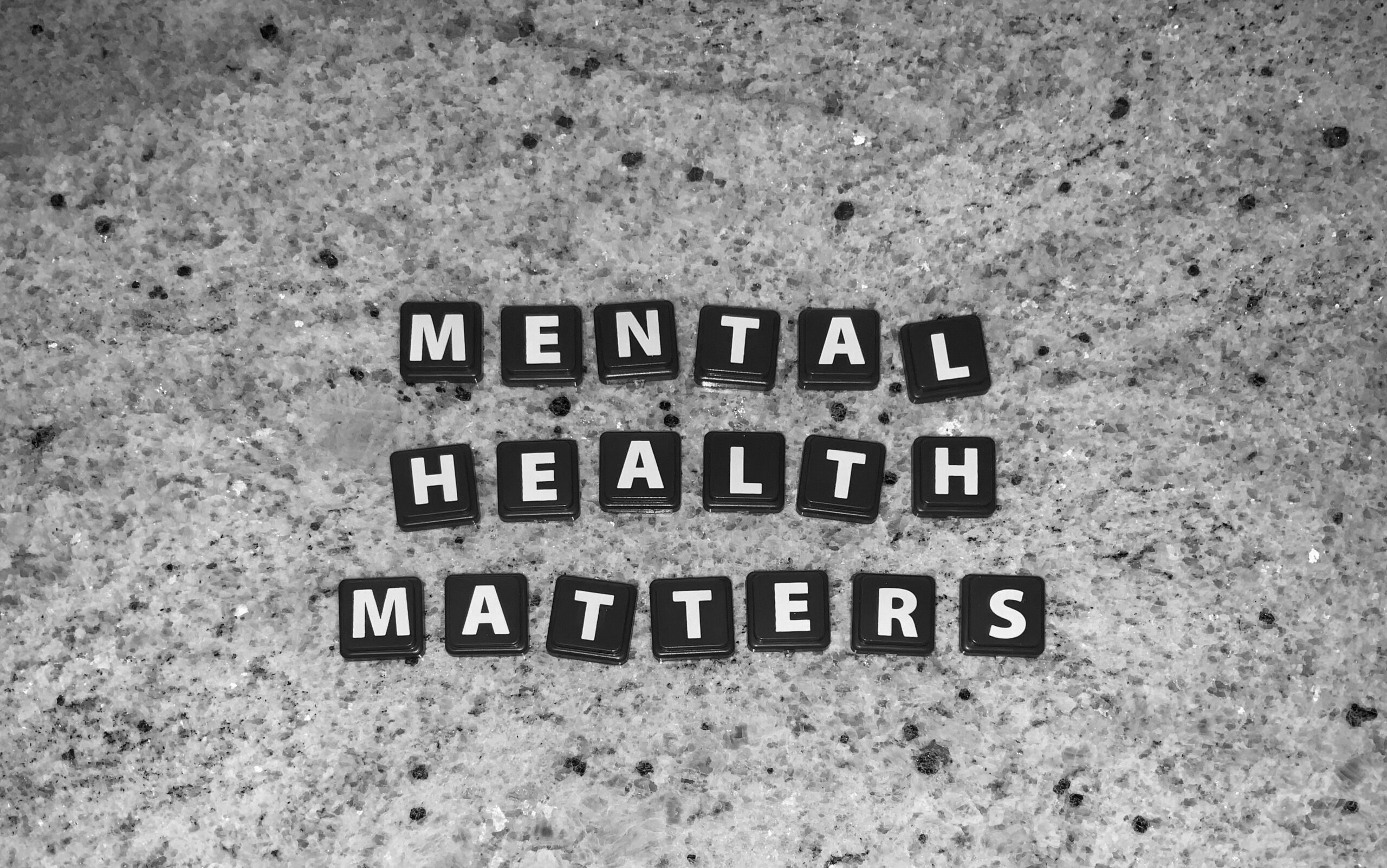 Black letter tiles on a speckled surface spell out MENTAL HEALTH MATTERS in three rows. The image is in black and white.